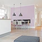 Essbereich mit Tisch, Stühlen und lila Wand. Küche mit Kücheninsel und Fenster.