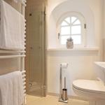 Badezimmer mit Dusche, Toilette, Waschbecken und Heizkörper mit Handtüchern.