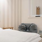 Schlafzimmer mit Bett, Fenster und Sitzgelegenheit.