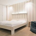 Schlafzimmer mit Bett, Kleiderschrank und Sitzgelegenheit.