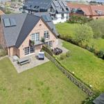 Haus mit Garten, Terrasse und Solaranlage. Umgeben von Grünflächen und Nachbarhäusern.