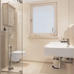 Badezimmer mit Dusche, Toilette, Waschbecken und Fenster.