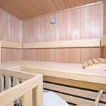 Holzsauna mit Sitzbänken und Thermometer an der Wand.