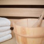 Holzschale mit Löffel und gestapelten Handtüchern in Sauna