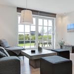Wohnzimmer mit Sofa, Tisch und Fenster zur Außenterrasse.