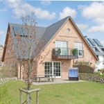 Ein Haus mit Terrasse, Garten und Sonnenschutz.
