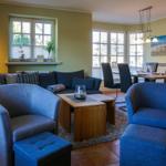 Wohn- und Essbereich mit blauen Sesseln, Sofa und Holztisch.
