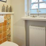 Toilette mit Mosaikwand, Fenster mit Vogeldekoration und Heizkörper.