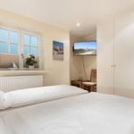 Schlafzimmer mit Doppelbett, Fenster, Kleiderschrank und Wand-TV.