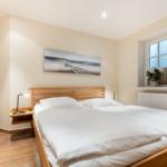 Schlafzimmer mit Doppelbett, Holzgestell und Fenster mit Blick.