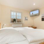 Schlafzimmer mit Doppelbett, Fenster, Fernseher und Wandbildern.
