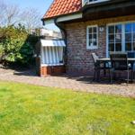 Hinterhof mit Terrasse, Garten, Liege und Tisch mit Stühlen.