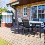 Terrasse mit Tisch, Stühlen und Strandkorb vor Backsteinhaus