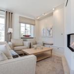 Wohnzimmer mit Kamin, Sofa, Tisch und Fenstern.