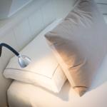 Bettkopfteil mit Kissen und Wandlampe.
