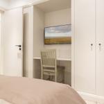 Schlafzimmer mit Schreibtisch, Stuhl und Fernseher an der Wand.