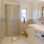 Bathroom with shower, sink, and toilet. Integrated Miele washing machine.