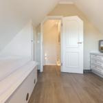 Bedroom with sloped ceiling, bed, dresser, and TV