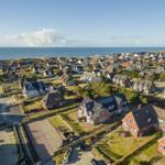 Aerial view of coastal village with houses and ocean in background.