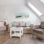 Living room with sofa, two chairs, and glass-top table under sloped ceiling.