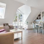 Living and dining area with sloped ceilings, glass doors, and wooden floor.