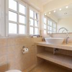 Badezimmer mit Waschbecken, Spiegel und Fenstern