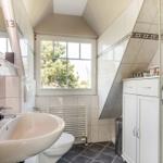 Badezimmer mit Dusche, Waschbecken und Fenster. Fliesen und weiße Möbel.