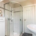Badezimmer mit Dusche, Waschbecken und Spiegel.