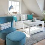 Ein Wohnzimmer mit blauem Sessel, grauem Sofa und weißem Couchtisch.