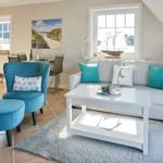 Wohnzimmer mit Sofa, blauer Sessel und Fenster mit Segelboot.