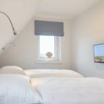 Schlafzimmer mit Doppelbett, Fenster und Wandbild mit Leuchtturm.