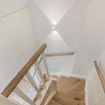 Hölzerner Treppenaufgang mit weißer Treppe und Handläufen