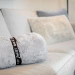 Graue Couch mit Kissen und einem gefalteten Handtuch.