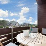 Terrasse mit Tisch und Stühlen, Blick auf Dächer und Himmel.