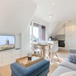 Wohn- und Essbereich mit TV, Sofa und Küche. Fenster zur Terrasse.