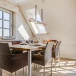Esszimmer mit Tisch, Stühlen und Fenster. Dachfenster und Balkontür sichtbar.
