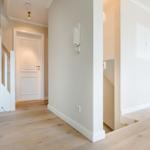 Hausflur mit Holzboden, weißen Wänden und Treppe zur oberen Etage.