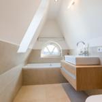Badezimmer mit Badewanne, Waschtisch und Dachfenster.