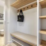 Entry area with bench, hooks, and shelves. Toilet and sink in the background.