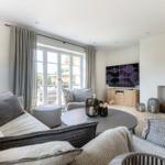 Living room with sofa, TV, and fireplace. Windows overlook the garden.
