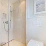 Shower with glass door, toilet, and wall picture