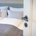 Door handle opens bedroom with bed and pillows.