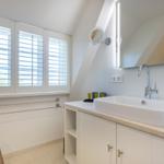 Bathroom with sink, mirror, and window with blinds.
