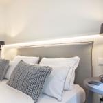 Bedroom with bed, pillows, and nightstand with lamp.