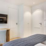 Bedroom with bed, wardrobe, mirror, and desk with TV.