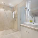 Bathroom with shower, sink, and lit mirror.