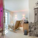 Sauna with pink lighting, two wooden rocking chairs, and lighthouse wall mural.