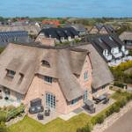 Farmhouse with thatched roof, terrace, and garden. Surrounded by other houses.
