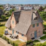 House with thatched roof and garden, view of town