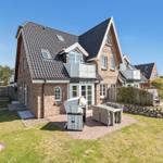 Haus mit Terrasse, Grill und Garten. Dachterrasse und Holzgeländer sichtbar.